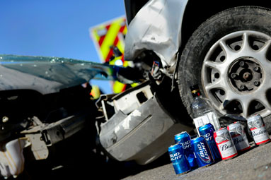 The front ends of two cars smashed together with alcoholic beverages in the foreground