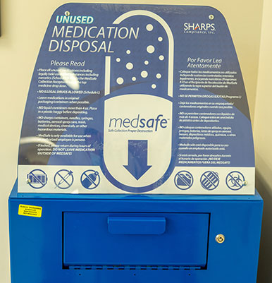 Blue bin used to dispose of drugs in a military pharmacy. A sign on top of the bin gives instructions about what can go in the bin