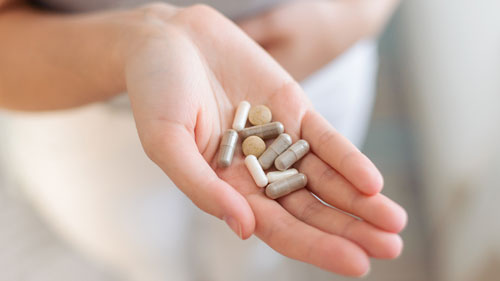 Woman's hand holding various supplements