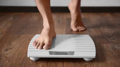 Picture of a man's feet stepping on a scale