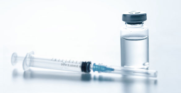 HPV Vaccine and a syringe sitting on a table