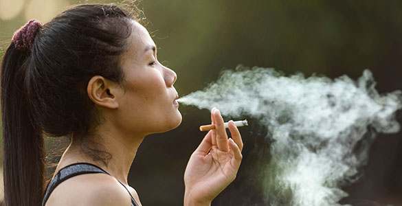 Woman smoking a cigarette, blowing smoke