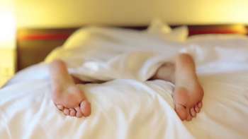 person in bed with feet hanging out, sleeping