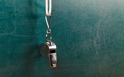 Coach's whistle hanging in front of a black board