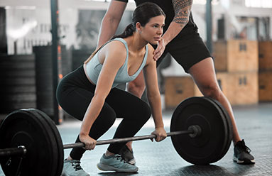 Woman being instructed on deadlift form