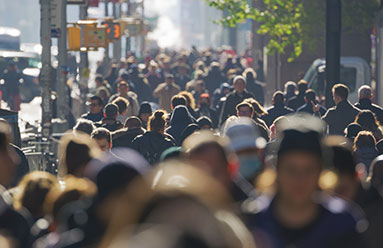 An anonymous group of people walking through the street in a crowd