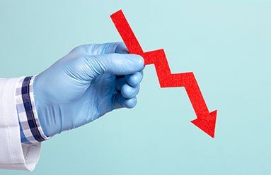 Hand wearing latex glove holding an arrow showing a downward trend