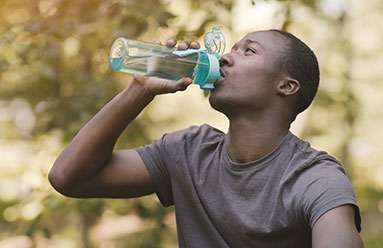 Black man drinking water from a reusable bottle