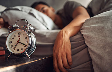 Man sleeping in bed, hand hanging off