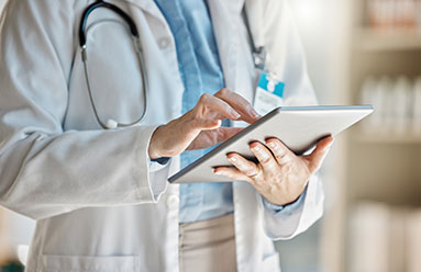 Cropped photo of a healthcare provider wearing a stethoscope and entering information on a tablet