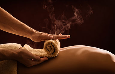 hot towel being unrolled onto a person's back during a massage