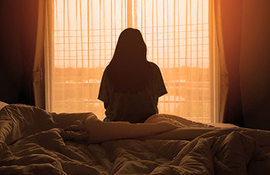 Woman sitting in a dark room feeling lonely