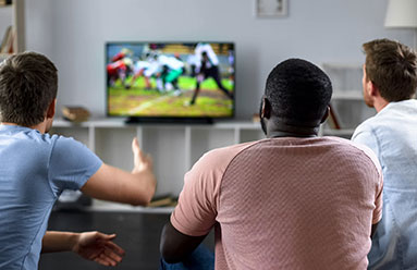 Three men watching a football game on tv.